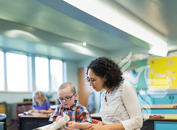 Educator helping young child with schoolwork in a classroom